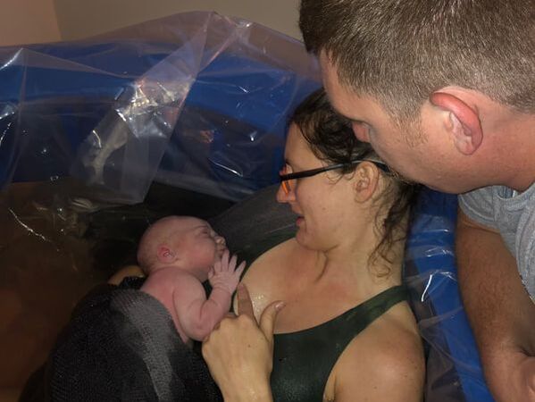 mom and baby bonding with dad looking over shoulder after water birth