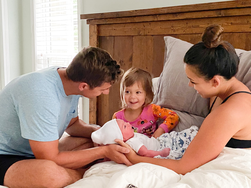 family on bed with newborn after home birth