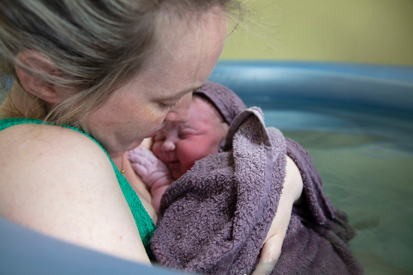 mom and newborn baby bonding in birthing tub after water brith