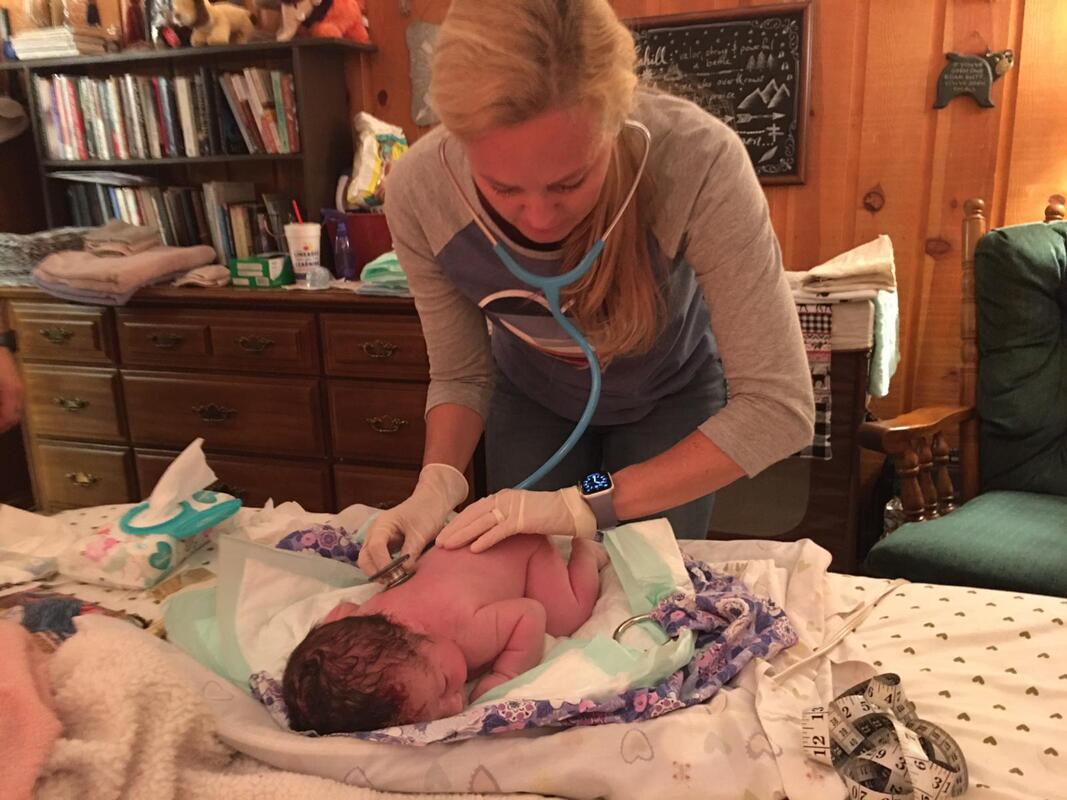 newborn baby receiving care from midwife after home birth